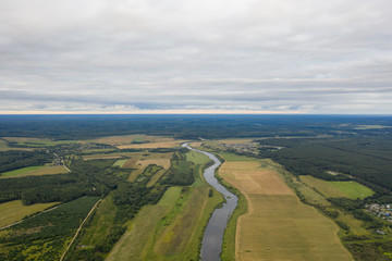 Fototapeta na wymiar flight over the river, field and pine forest on a cloudy summer day (photo from drone )