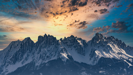 Fototapeta na wymiar Snowy rocky mountain with a beautiful cloudy dramatic sunsetspace fort text