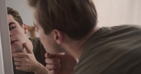 Handsome man getting ready while checking his hairstyle and face in mirror