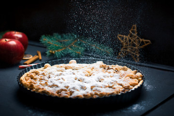 Apple pie sprinkled with sugar on a festive decorated table