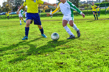 Obraz premium young football players. Children play a soccer game. Legs in action with a ball, dribbling