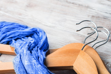 Clothes hangers with classic blue female foulard on wooden background