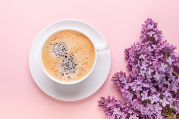 Lilac and cup of coffee on pink background. Still life. Spring romantic mood. Top view. Copy space