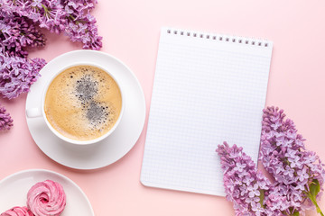 Lilac, cup of coffee, homemade marshmallow, notepad on pink background. Still life. Spring romantic mood. Top view