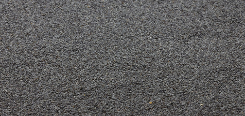 Raw blue poppy seeds scattered on a flat surface. Background. Tор view .