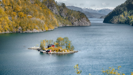 small inhabited island in the fjord of Norway against the backdrop of mountains and blue water in...