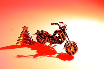 Toy motorcycle with metal parts and a Christmas tree. Motorcycle model isolated on brick wall background with slight shadow and reflection. 