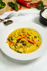 Green curry traditional Thai food name in Thai is Gaeng Kiew Waan in white round ceramic plate vertical frame