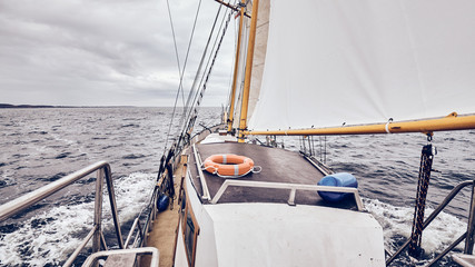 Sailing old schooner on a stormy weather, color toning applied.