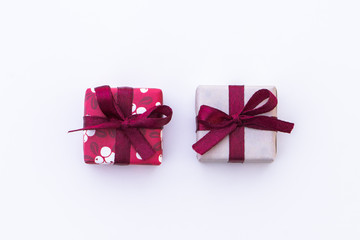 Two small presents on white background. Gifts wrapped in red, white and gray paper with maroon ribbons and bows. Could be for christmas presents. Old Scandinavian style.