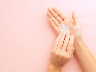 hands applying cream on pink background