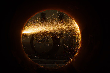 Sparks of plasma cutting inside a large diameter pipe.