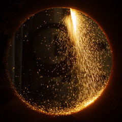 Sparks of plasma cutting inside a large diameter pipe.