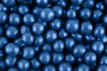 Candy sugar pearls, cake decoration, copy space. Small silver sparkle balls texture. Classic blue background. Color of the year 2020. Top view, flat lay