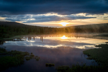 Russian northern landscape. Kola Peninsula, the Arctic. Murmansk region. Swamp with morning haze at sunrise