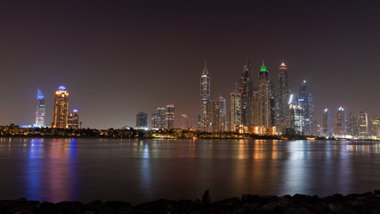 Fototapeta na wymiar Dubai skyline at night with lights on the water and luxirious skyscrapers of UAE