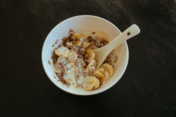 Muesli with banana in white bowl with spoon