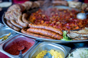 Spicy sausages and different grilled meat at street food market