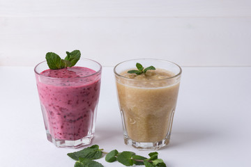 Blackcurrant smoothie and celery, apple and banana smoothie in glass cups on a white background, copy spase