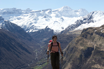 Hiker woman arriving at the Ripeyre pass, in the background the snowy Gavarnie cirque, its main...