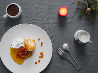 Cheesecakes or curd pancakes with cream and sea buckthorn jam on a white plate, on a gray tablecloth. Vintage gravy boat, espresso.Homemade сottage cheese fritters. Tasty breakfast. Top view.