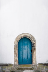 Arched wooden door. Old blue door and a white wall. Just a door