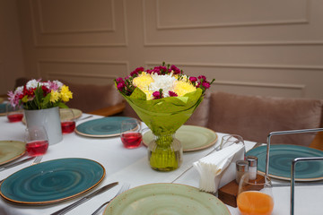table setting in restaurant with flowers bouquet and plates for guests