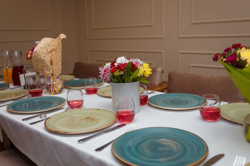 festive table setting with plates, flowers and wine or juice in glasses
