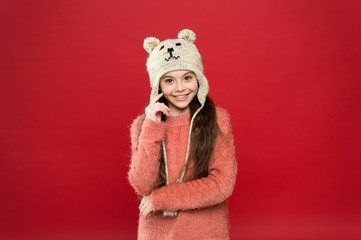 Obraz premium Happiness and joy. Winter outfit. Little kid wear knitted hat. Little girl winter fashion accessory. Small child long hair wear hat red background. Cute model enjoy winter style. Adorable small bear