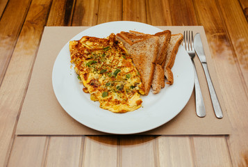 Omelet with vegetables and bread toast on white a plate