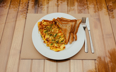 Omelet with vegetables and bread toast on white a plate