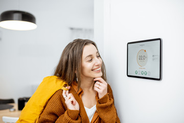 Happy woman feeling warm by coming home. Enjoying smart home remote heating control