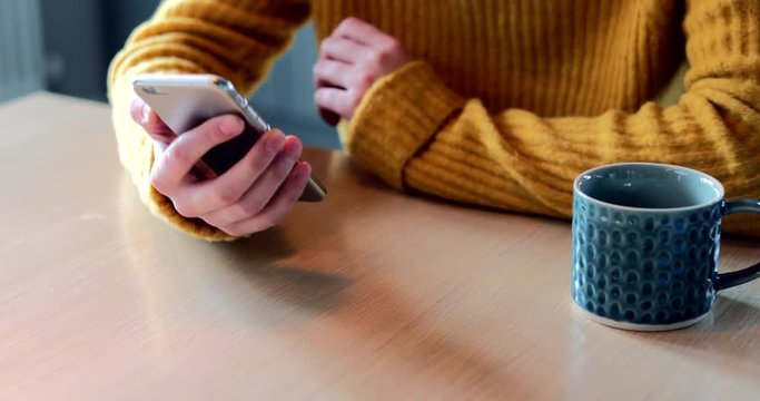 Woman Concerned About Excessive Use Of Social Media Laying Mobile Phone Down On Table