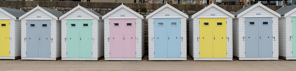 Panoramic photo of a row of beach huts at Lyme Regis in Dorset.