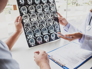 The doctor evaluates the brain X-ray and advise patients on health care, medical checkup concept