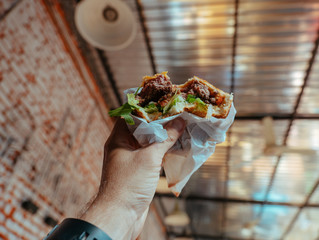 Tasty Hamburger with ham and salad in the man's hand