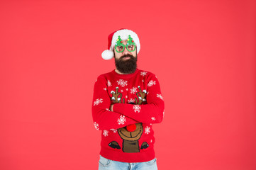 Come get ready for Christmas. bearded man santa hat red wall. christmas time. male xmas party glasses. happy new 2020 year. funny hipster knitted sweater. knitwear fashion. winter holiday celebration