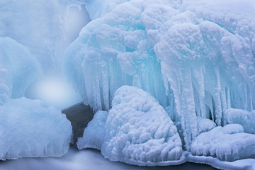 Winter landscape of cascade captured with motion blur and framed by blue ice, Gull Creek, Michigan, USA