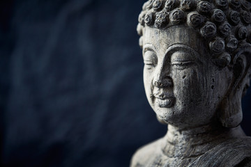 Fototapeta na wymiar Meditating Buddha Statue on dark background. Copy space. 