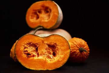 Composition of cut half pumpkins on a black background