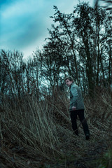 Man in jacket walking between reed in autumn.