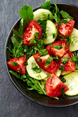 Salad with Tomatoes, Cucumber and Rocket on stone Background. Healthy Snack Idea. Close up. Top view. 