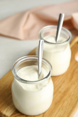 Tasty organic yogurt in glass jar on wooden board