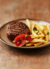  Hamburger steak with french fries and tomatoes. Brown stone background. 