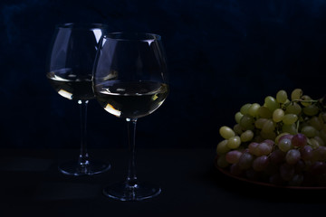 white wine and grapes on a dark background