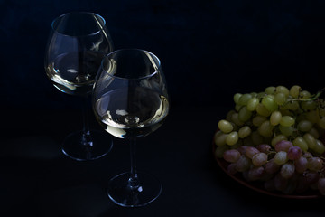 white wine and grapes on a dark background