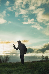 Man with handgun in countryside at sunset.