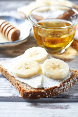 Healthy Breakfast Idea. Banana Sandwich with cream cheese and  acacia honey on white wooden background. Close up. 