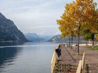 Lonely sad woman looking down at the water of Lake Como, Italy. Sunny autumn day