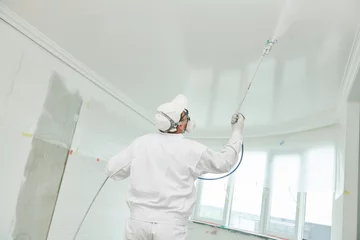 Foto op Aluminium Painter worker with airless painting sprayer covering ceiling surface into white © Kadmy